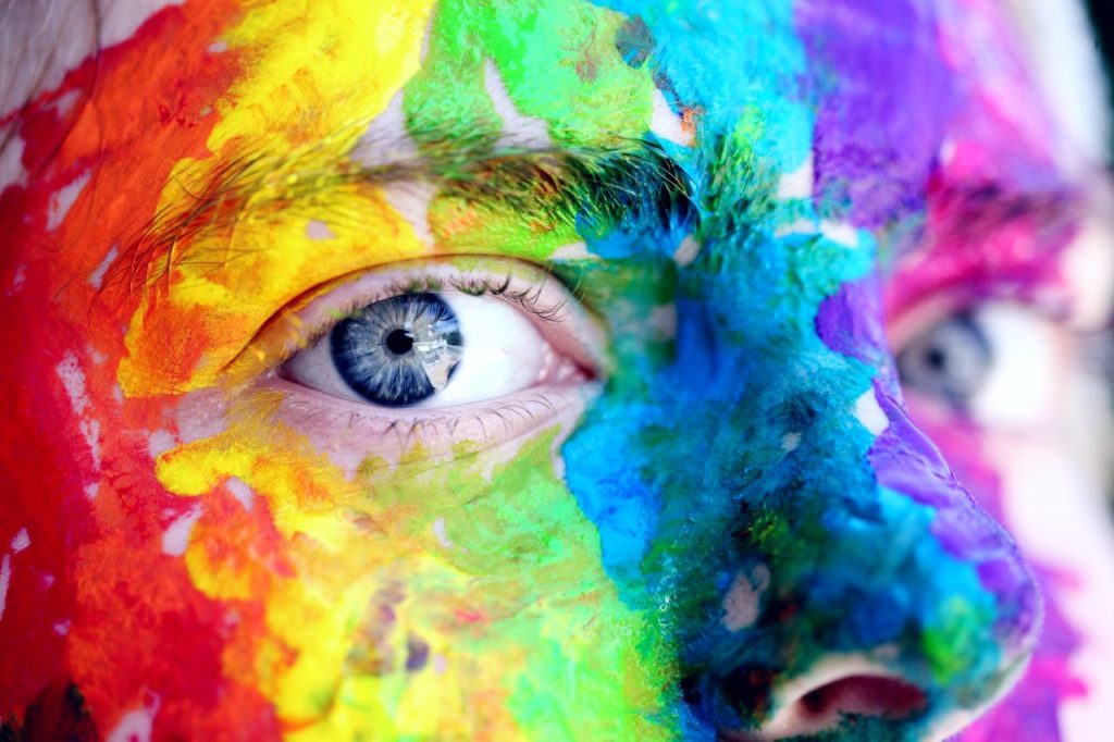 person-with-body-painting-1209843 Close-up of a person with colorful rainbow face paint, symbolizing LGBT pride and expression.